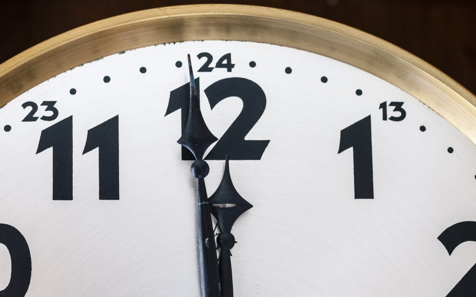 Närbild på en väggklocka som visar tiden en minut i tolv.