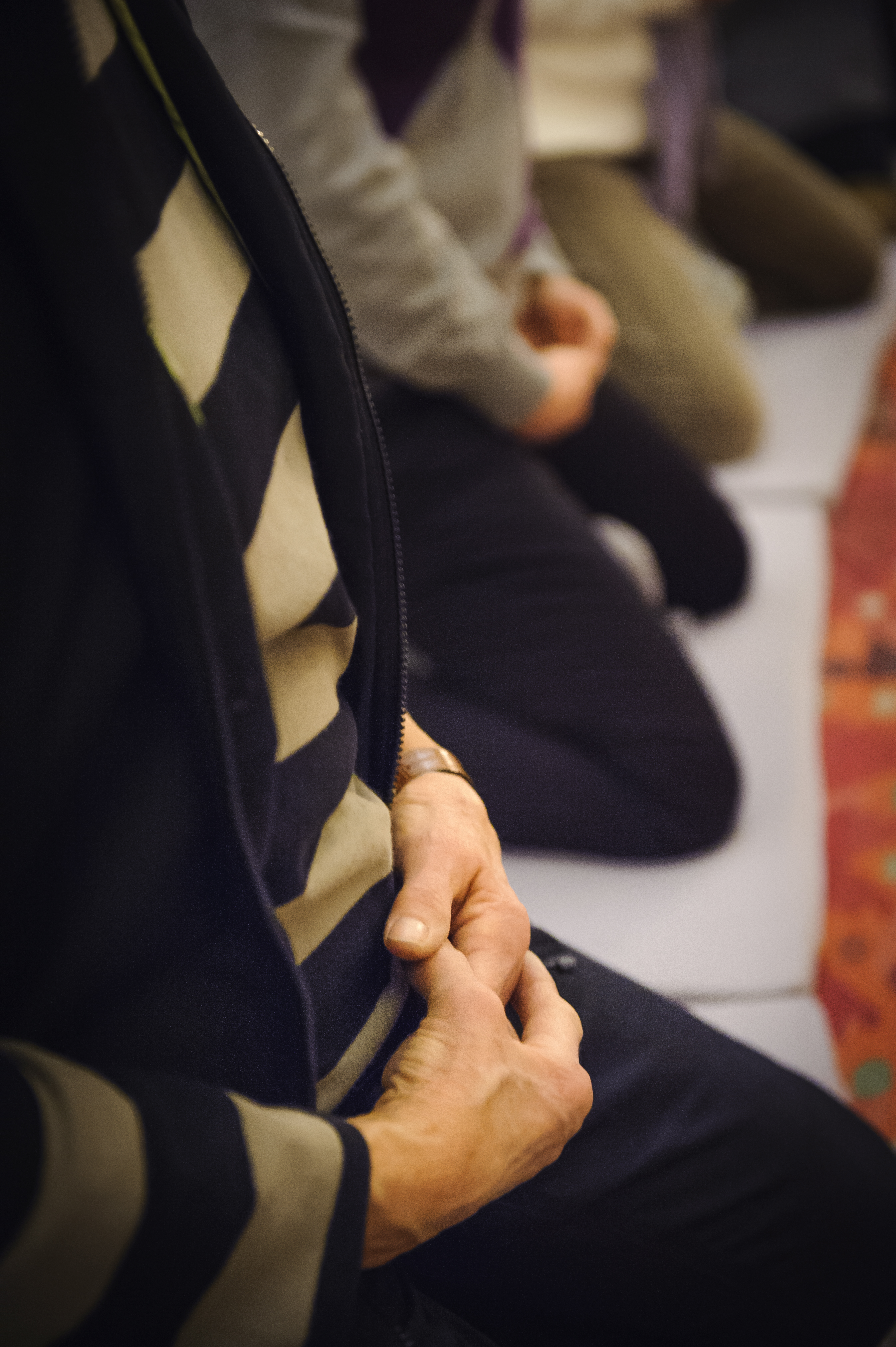 Några personer sitter på knä på golvet med knäppta händer.