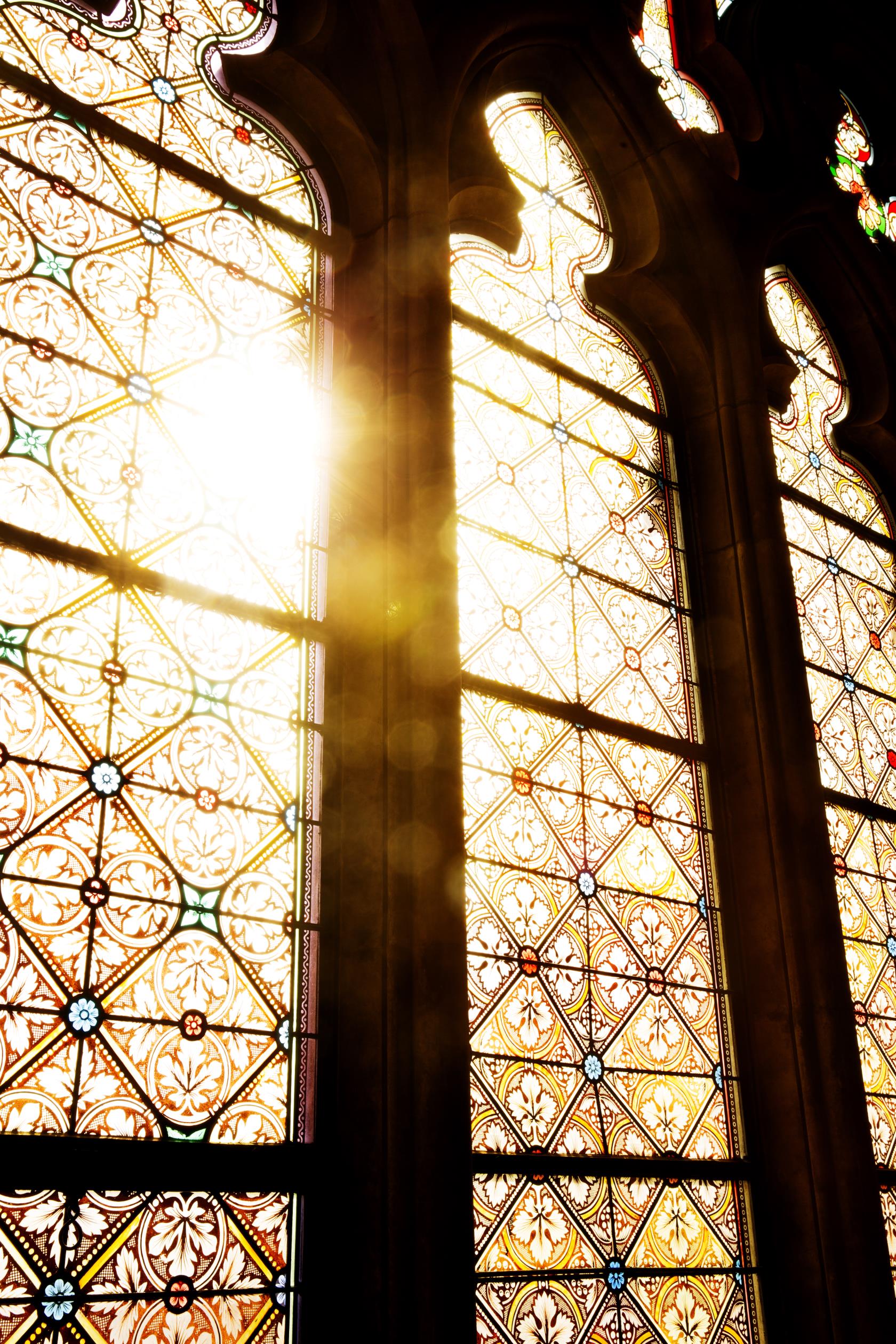 Solen lyser igenom ett stort kyrkfönster.