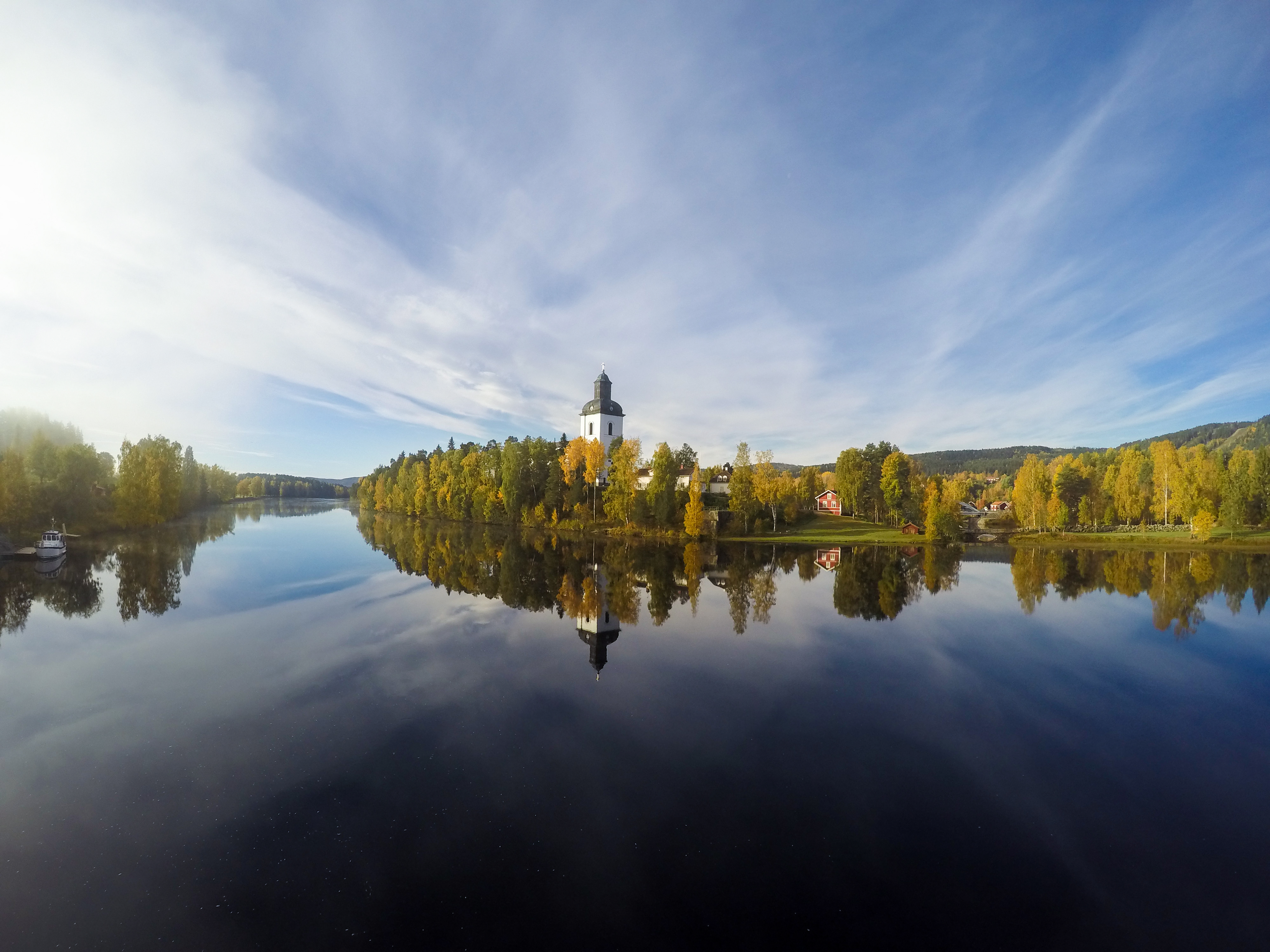 En kyrka vid vattnet reflekteras i den stilla vattenytan.