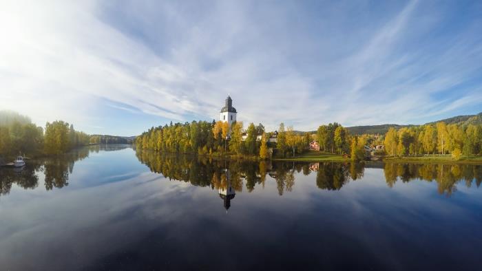 En kyrka vid vattnet reflekteras i den stilla vattenytan.