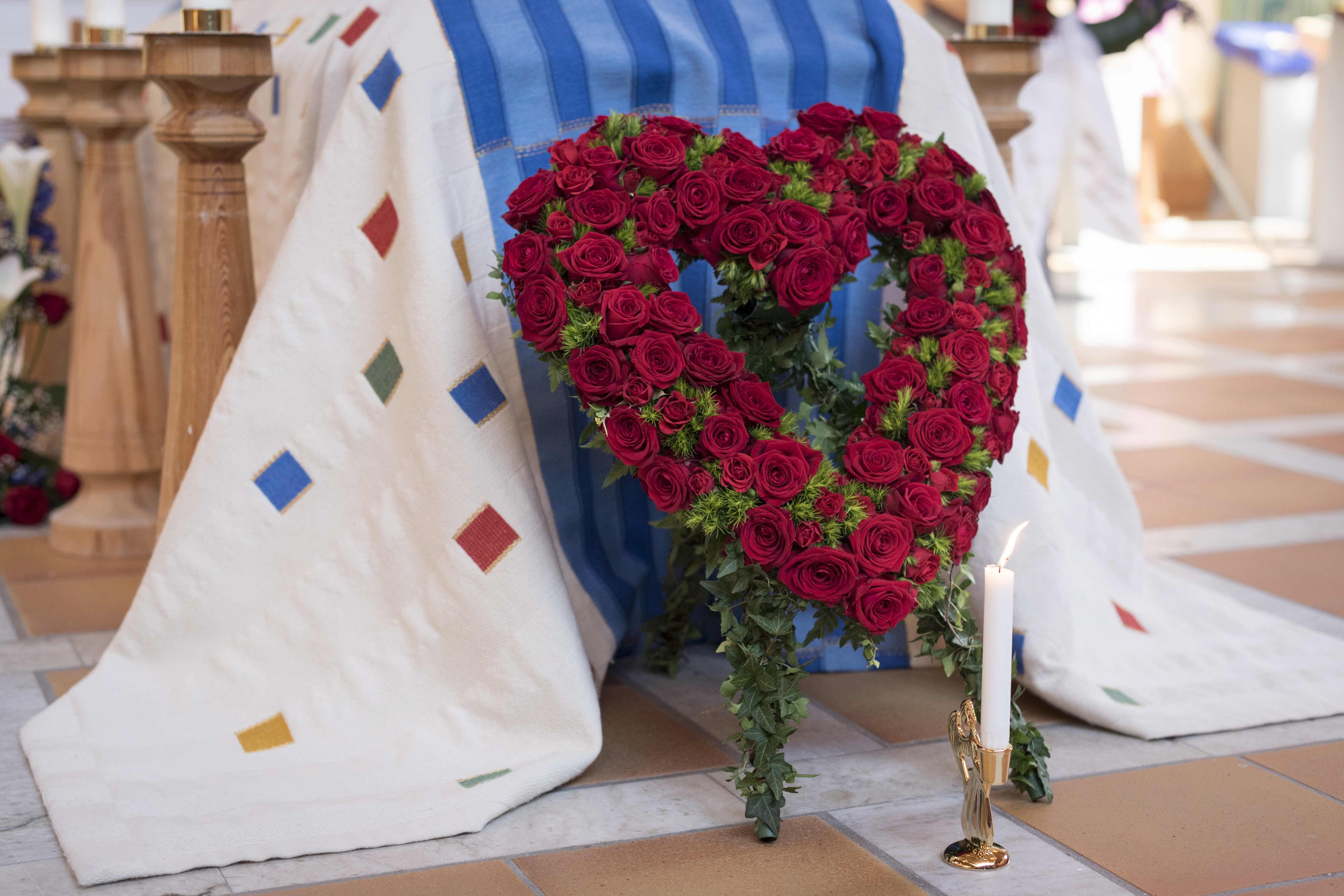 En begravningsbukett i form av ett hjärta av röda rosor står framför en kista.