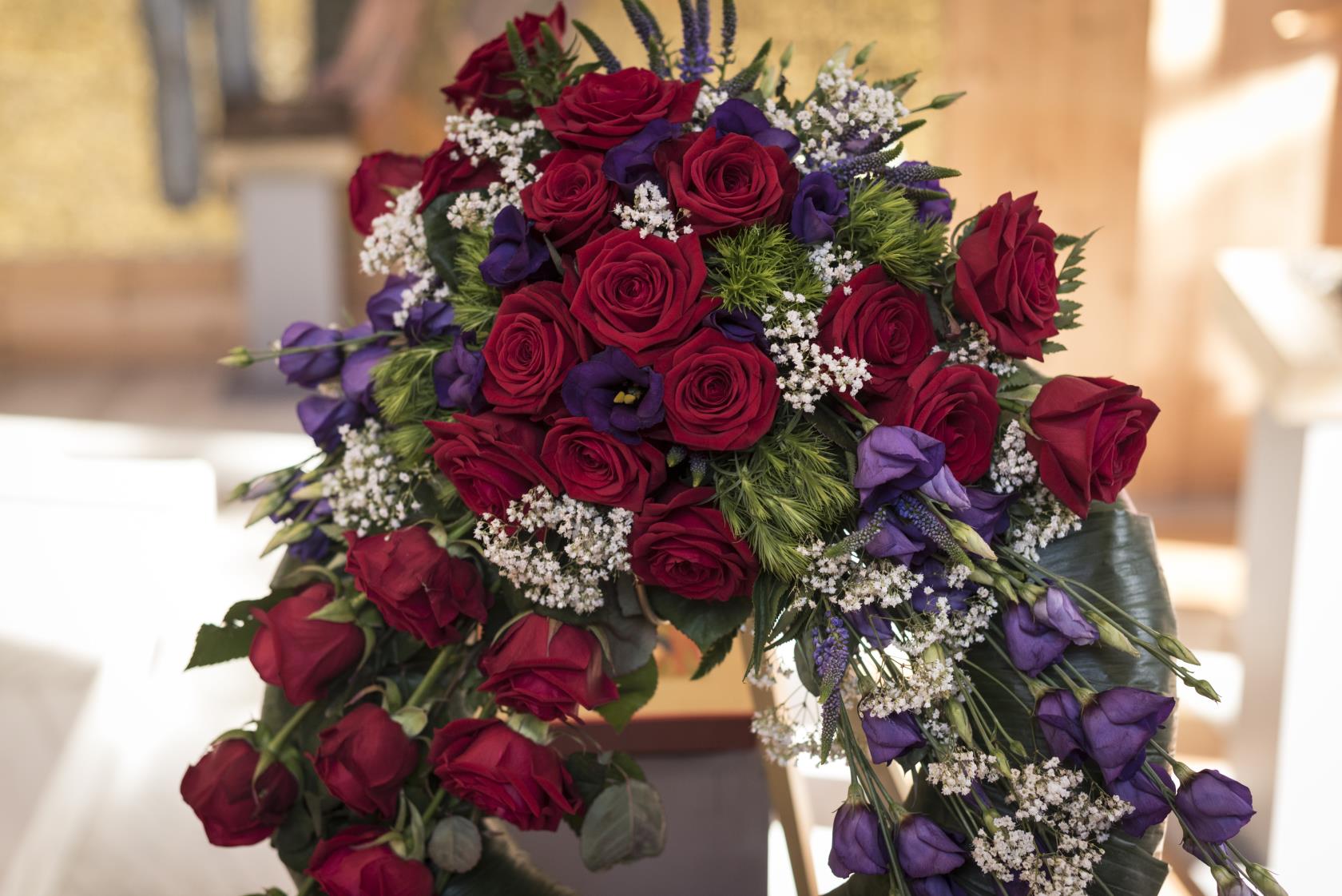 En begravningsbukett av röda och lila blommor.