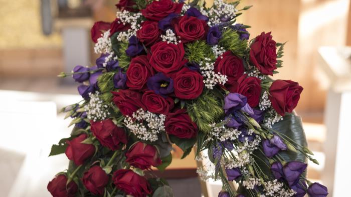 En begravningsbukett av röda och lila blommor.