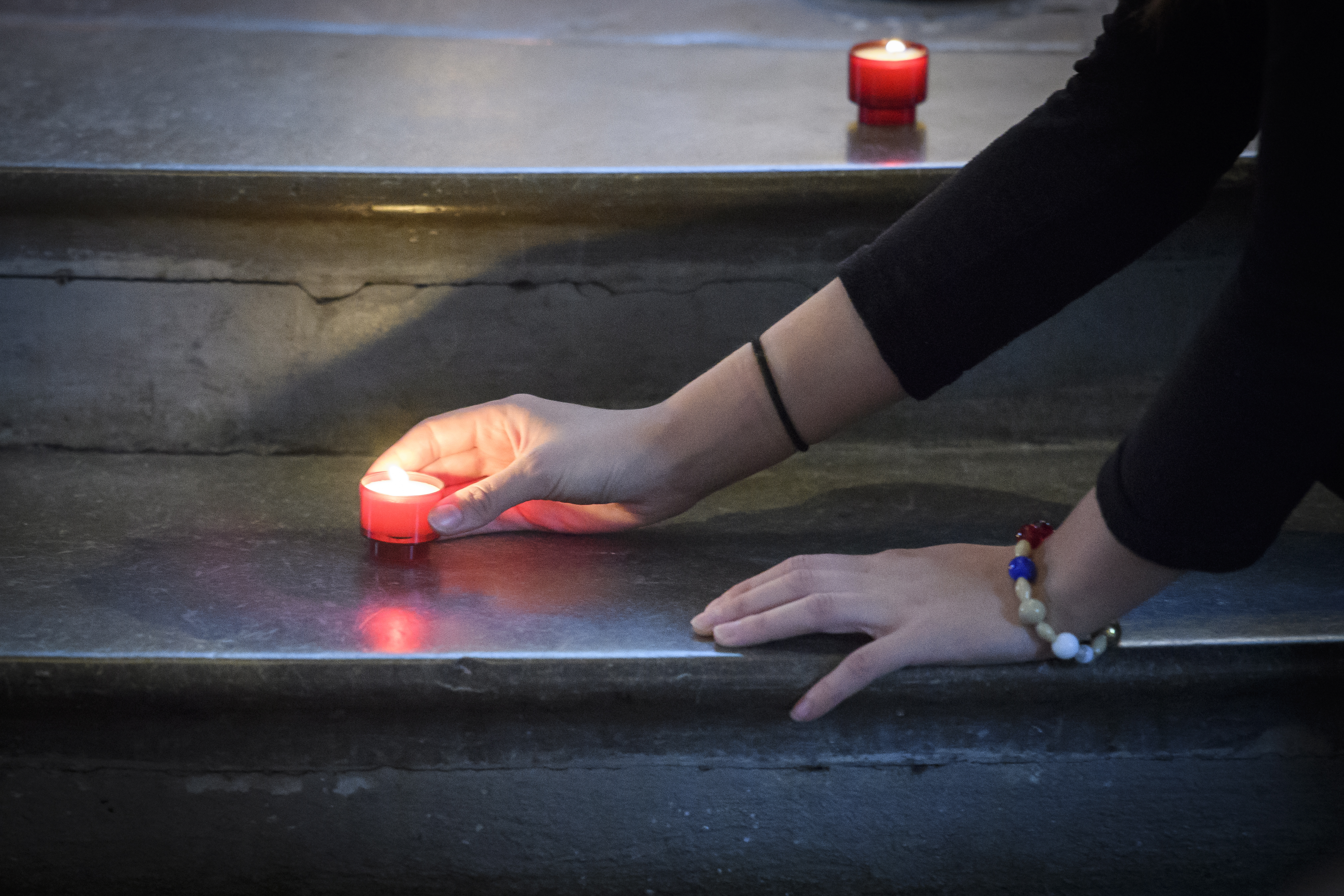 En person ställer ut värmeljus i en trappa.