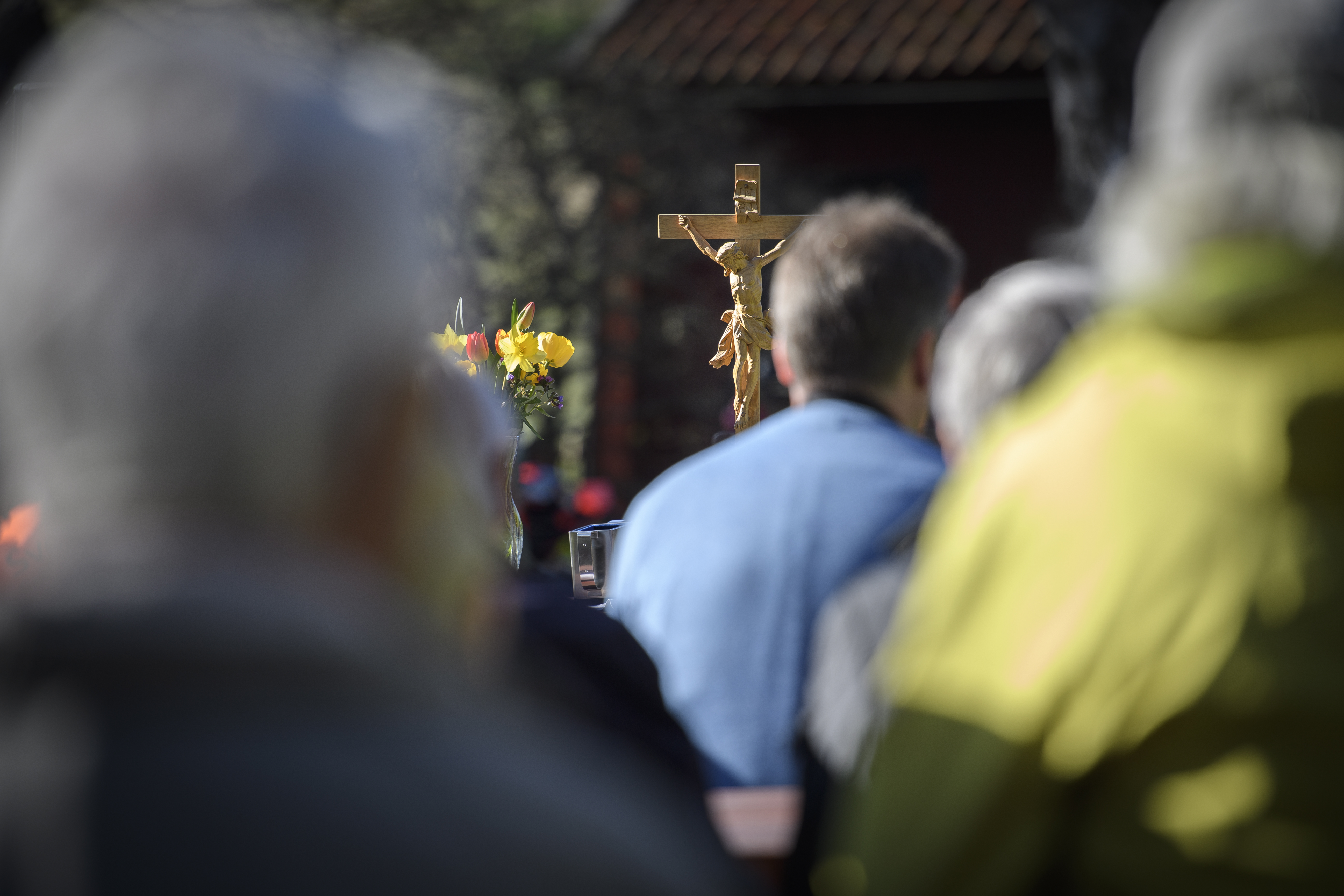 Ett altare med ett träkrucifix. Suddiga människor i bakgrunden.