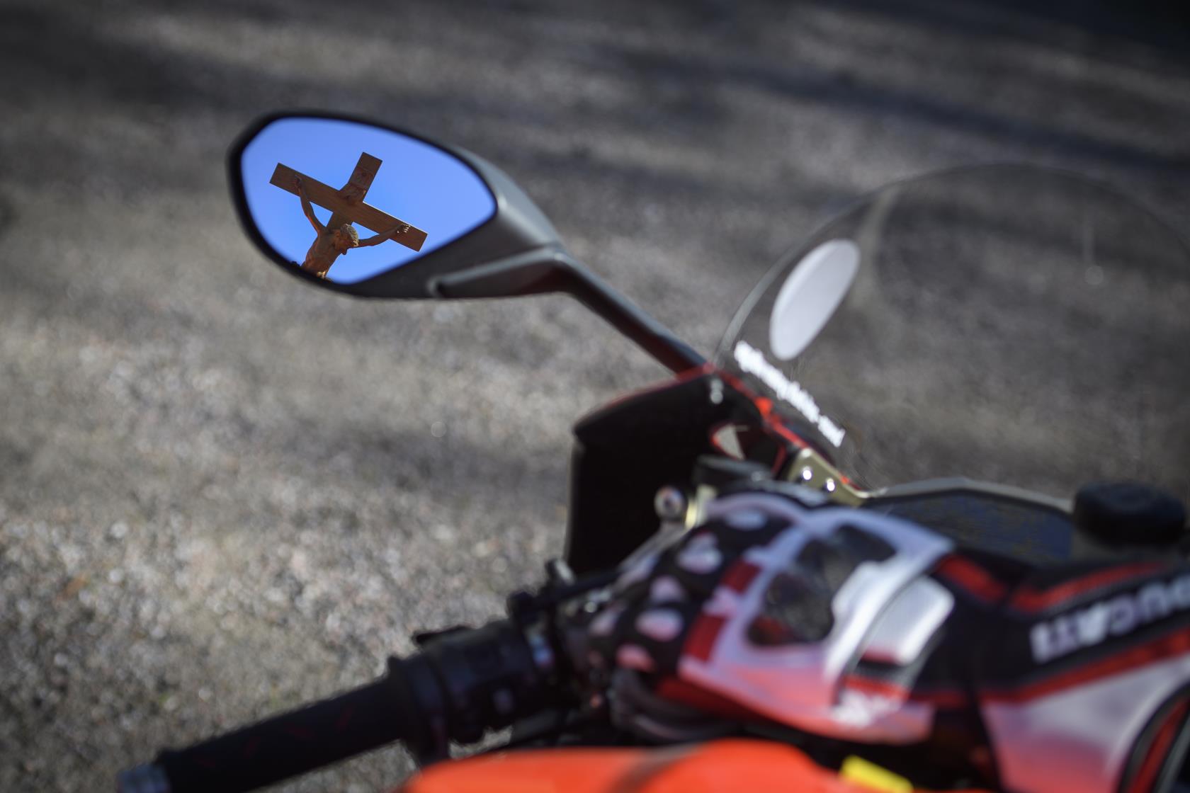 Ett krucifix reflekteras i backspegeln på en motorcykel.