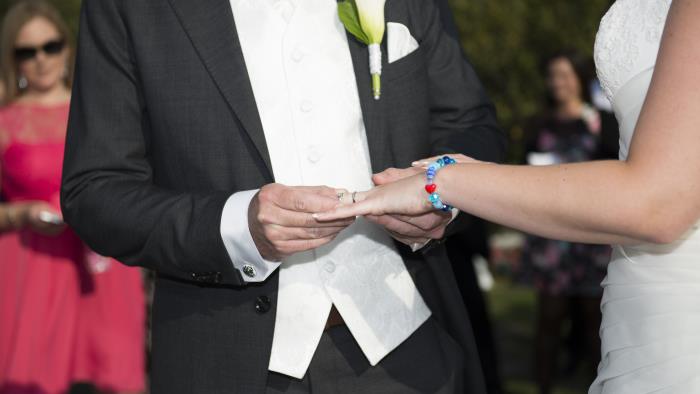 En brudgum trär vigselringen på brudens finger.