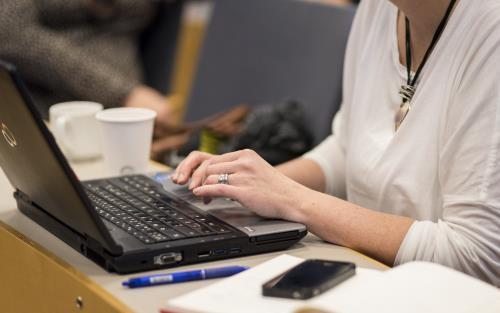 En person sitter och arbetar på sin laptop.