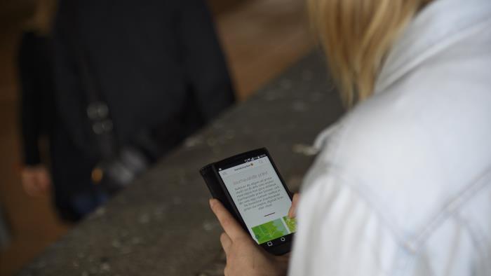 En kvinna sitter utomhus och håller på med sin mobiltelefon.