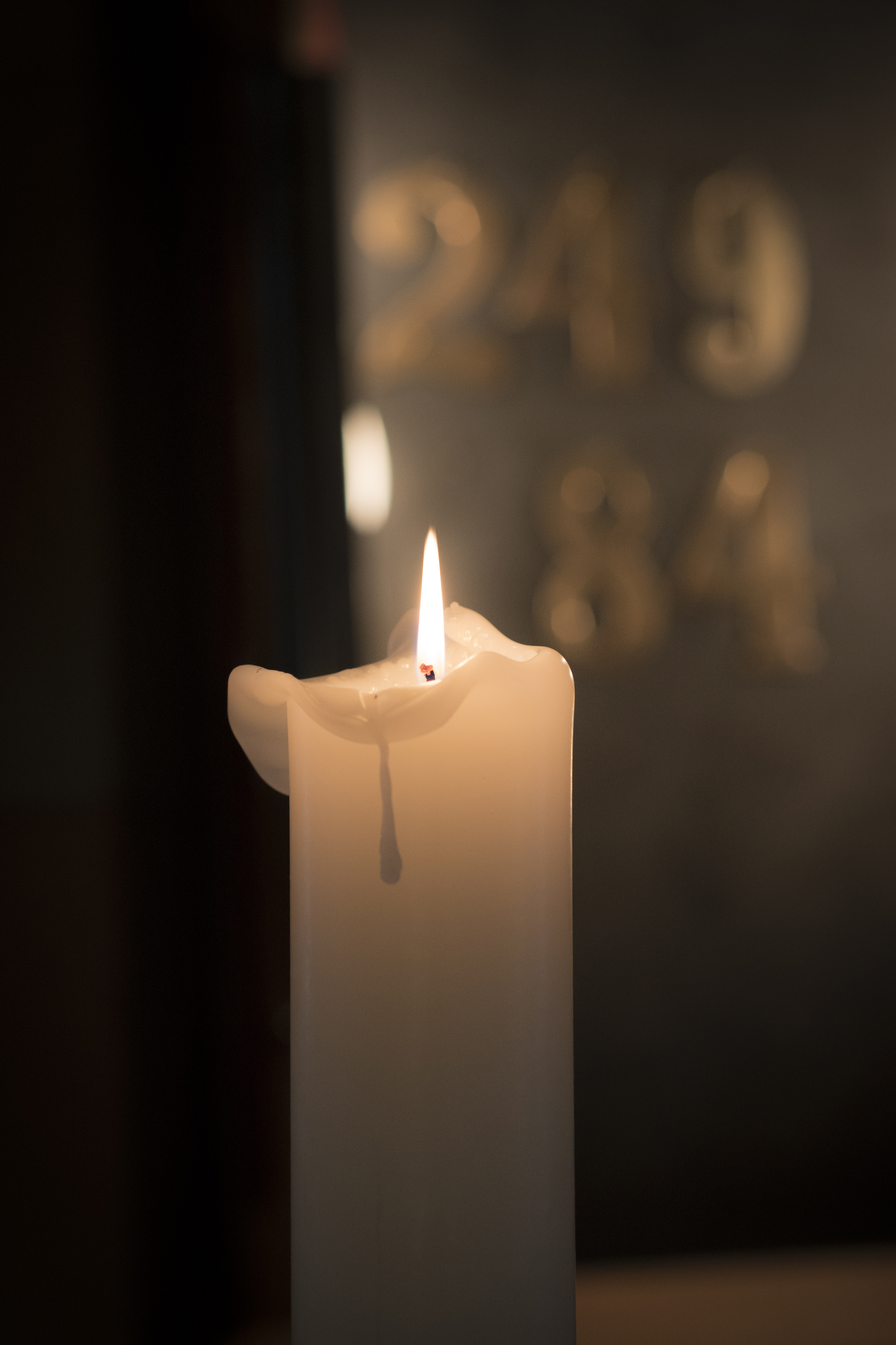 Ett tänt stearinljus och en psalmnummertavla i bakgrunden.