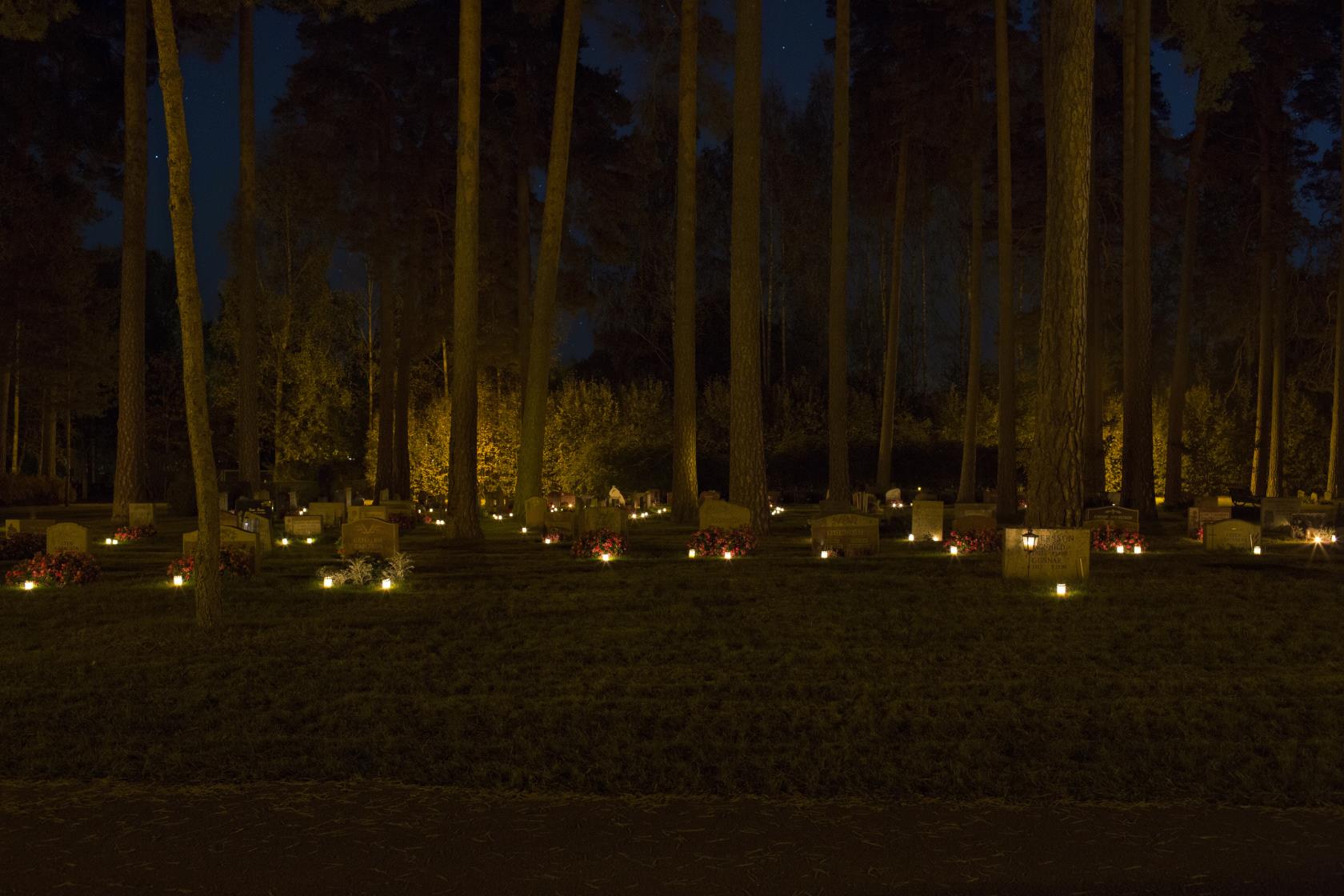 Gravljus som lyser i mörkret på en kyrkogård.