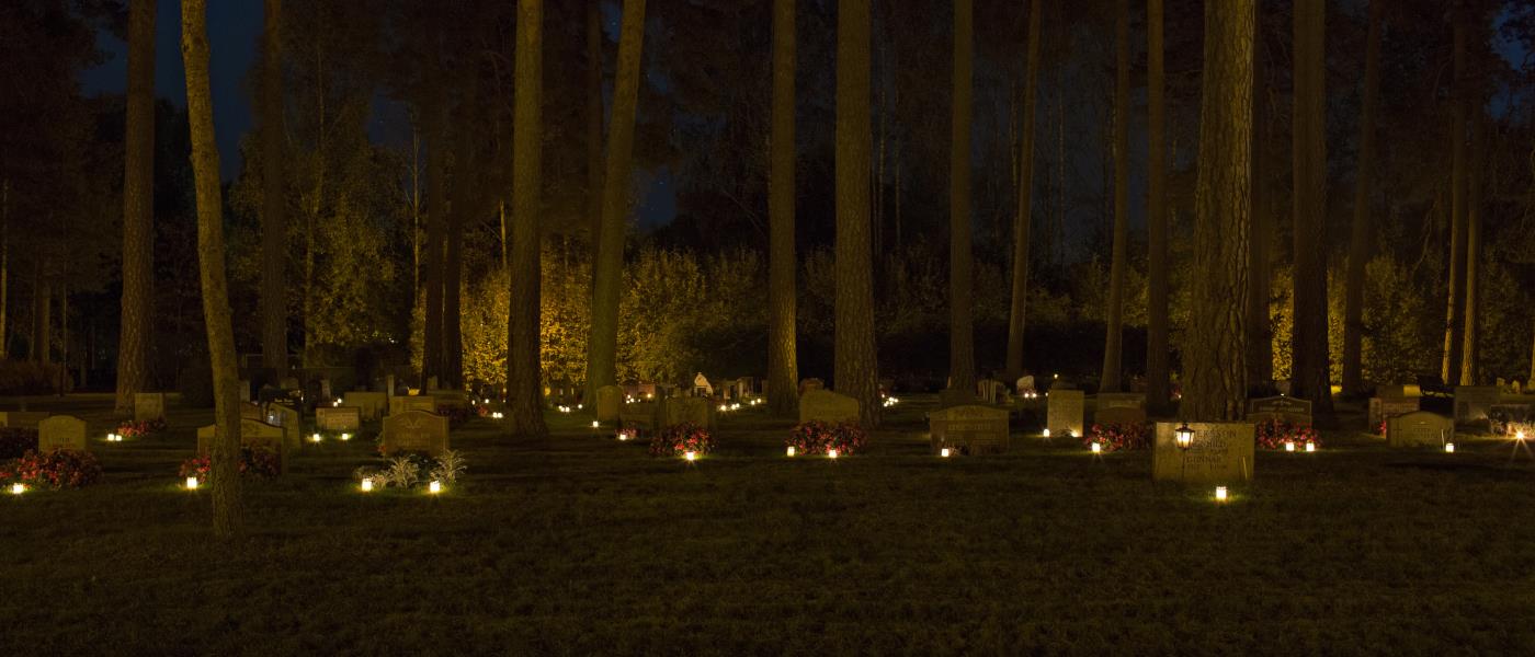 Gravljus som lyser i mörkret på en kyrkogård.