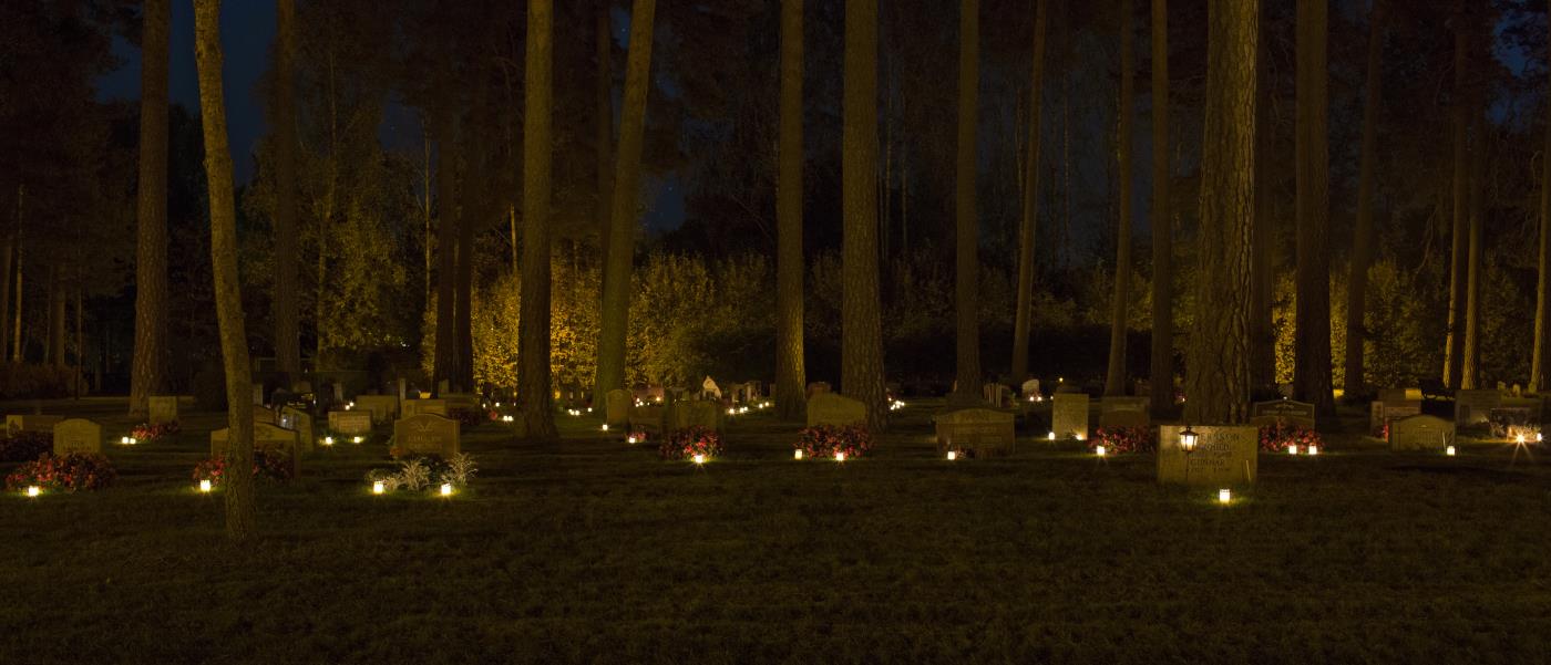 Gravljus som lyser i mörkret på en kyrkogård.