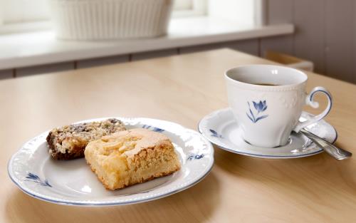 En kopp kaffe och ett fat med fikabröd står på ett bord.