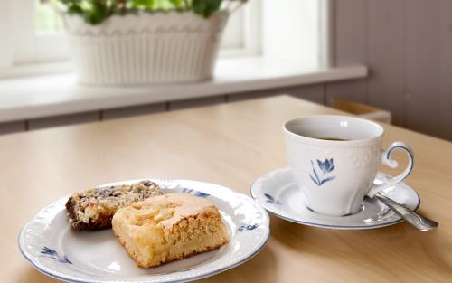 En kopp kaffe och ett fat med fikabröd står på ett bord.