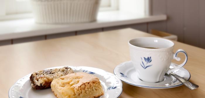 En kopp kaffe och ett fat med fikabröd står på ett bord.