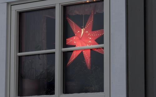 En röd adventsstjärna lyser i ett fönster.