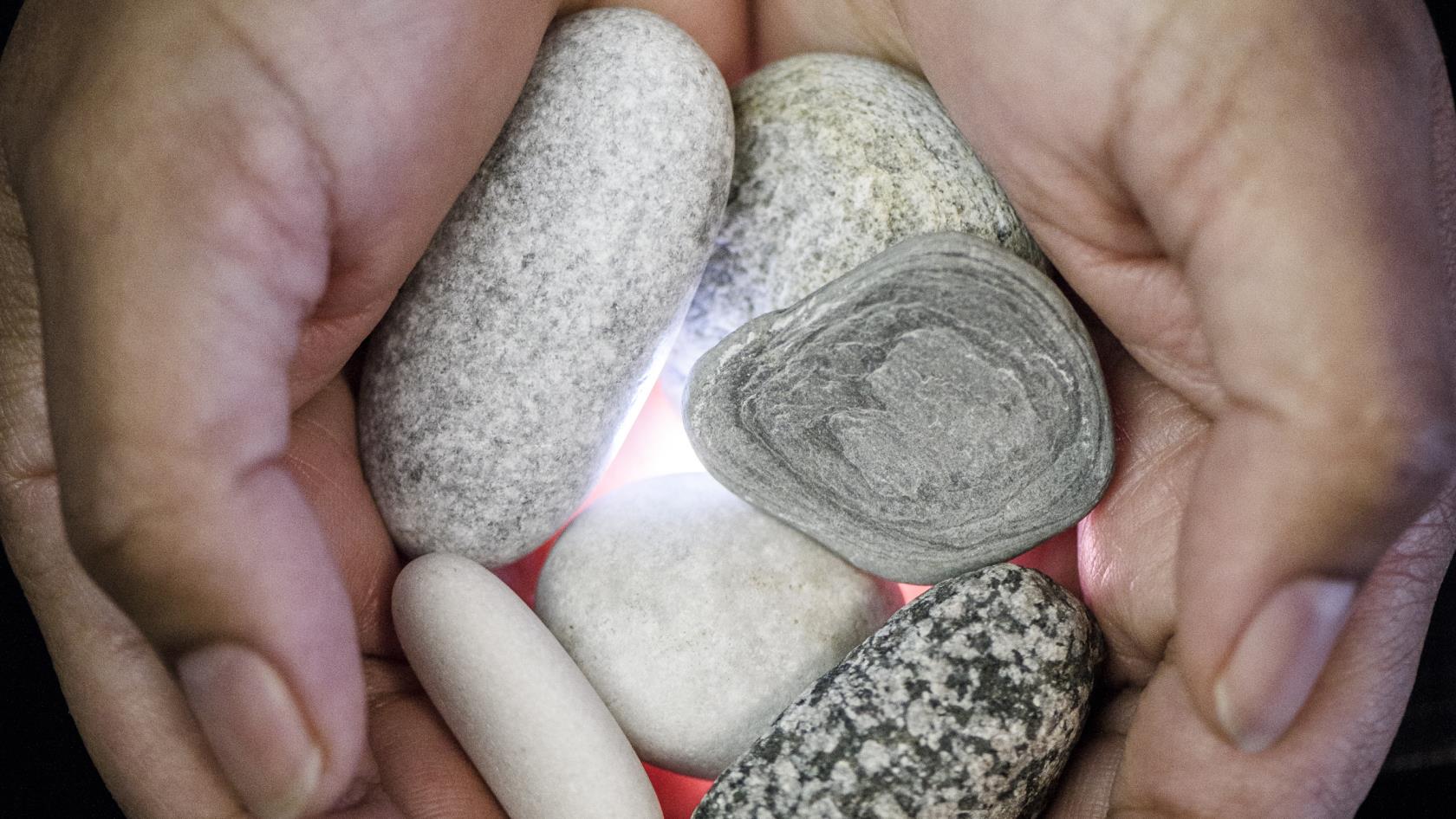 Närbild på en person som håller fram några stenar i handflatorna.