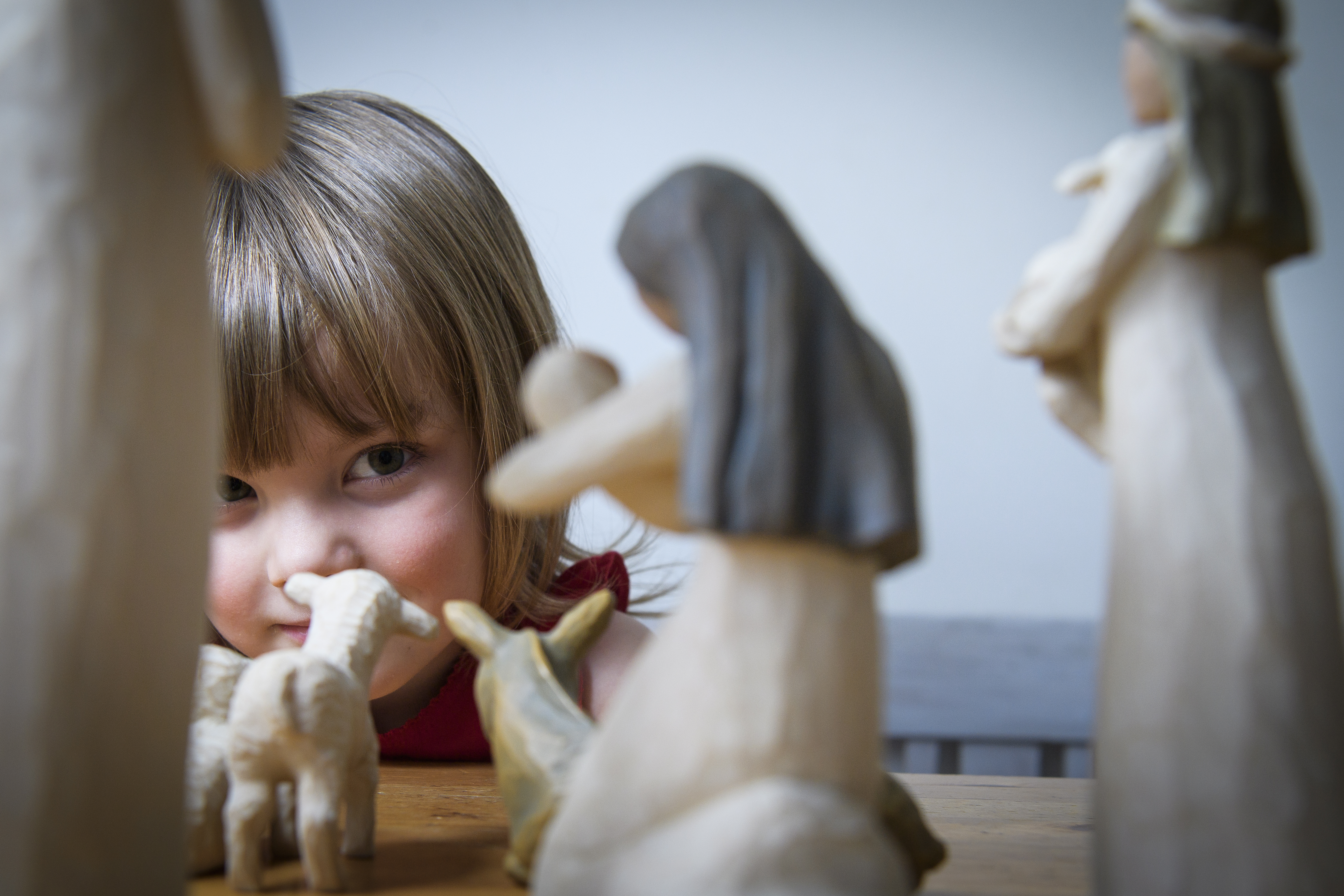 Närbild på en liten flicka som tittar på några figurer i en julkrubba