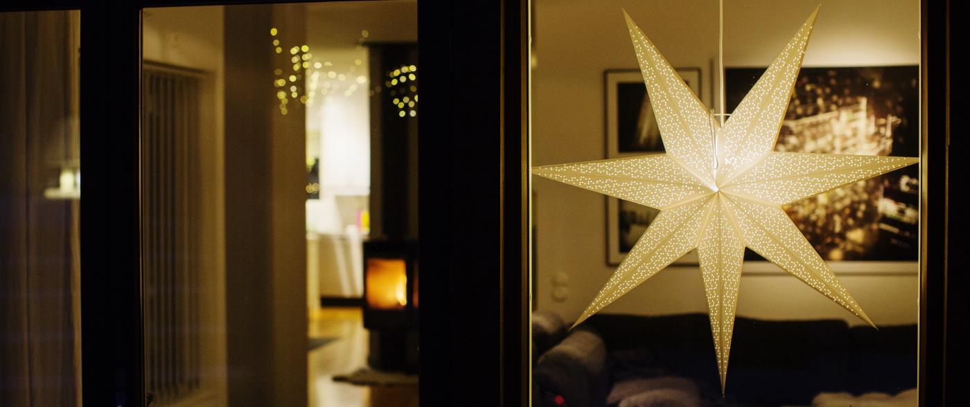 En adventsstjärna lyser i ett vardagsrumsfönster.
