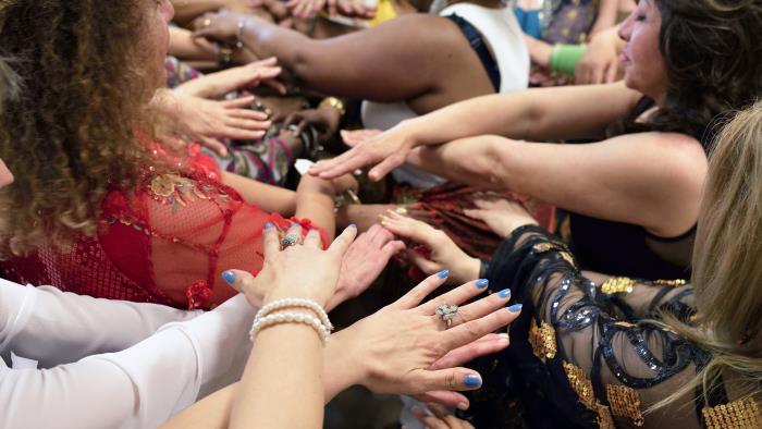 En grupp kvinnor sträcker sina armar in mot mitten.