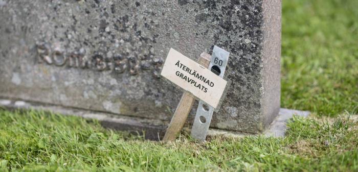 En liten skylt med texten Återlämnad gravplats står vid en gravsten.