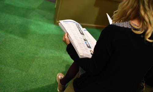 En kvinna sitter i en monter och bläddrar i en tidning.