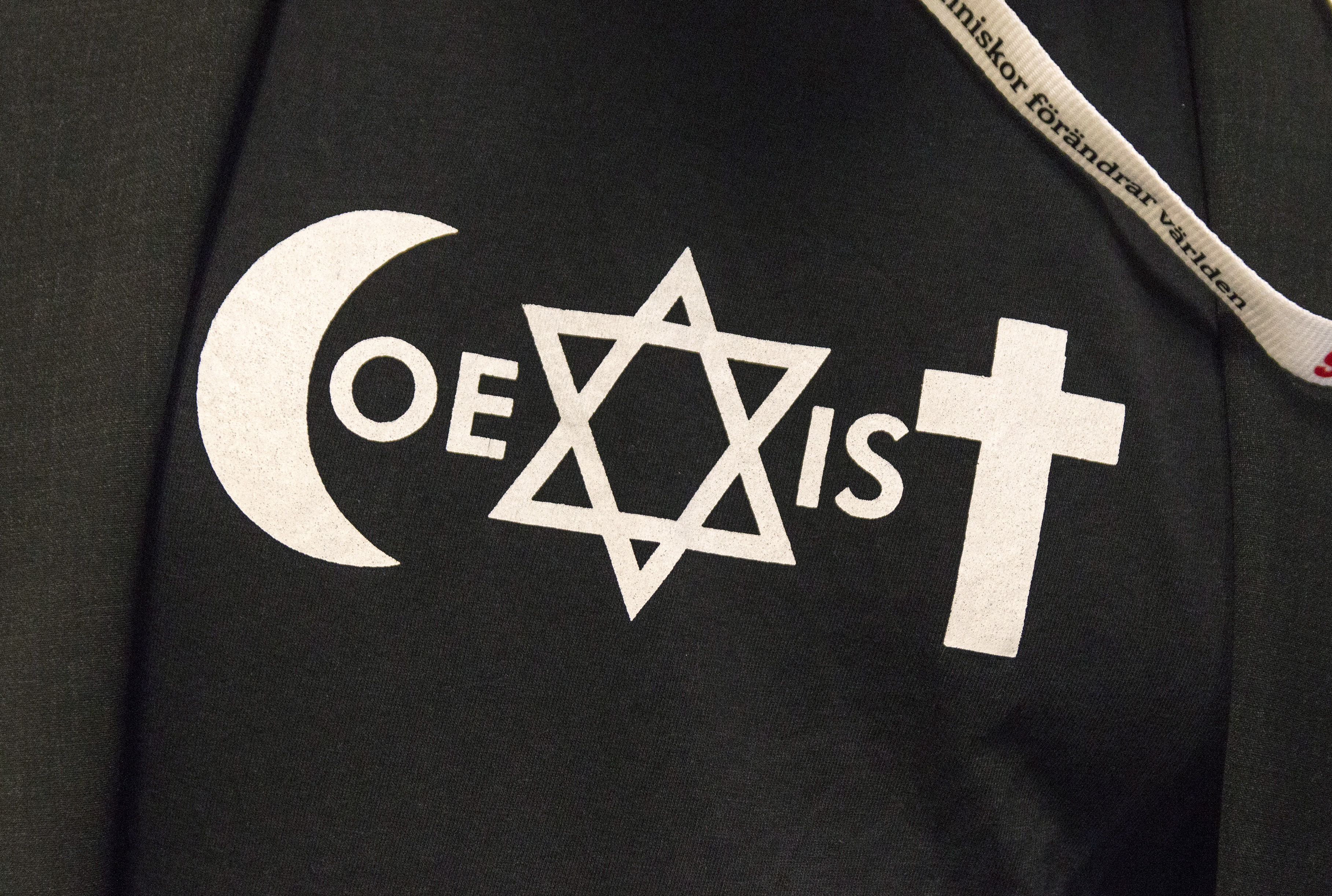 Symbolerna för islam, judendom och kristendom bildar tillsammans ordet Coexist på en tröja.