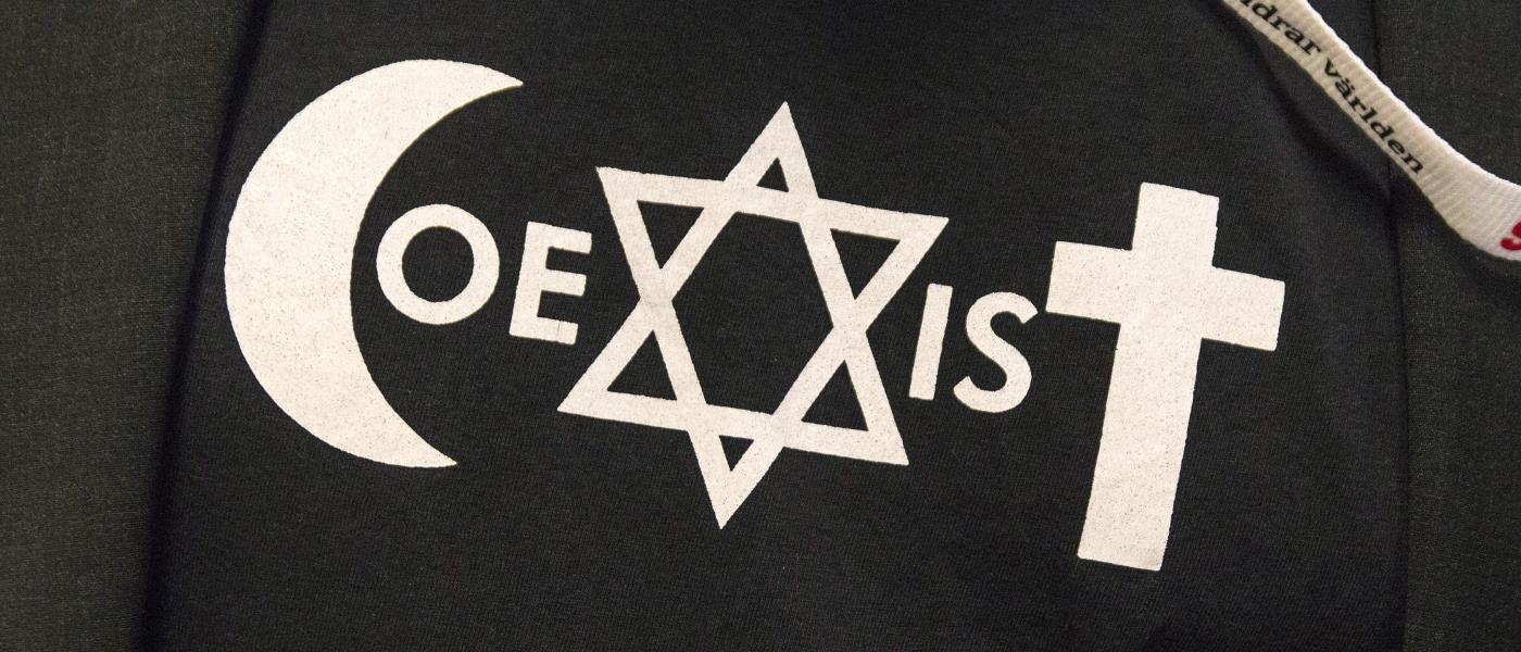 Symbolerna för islam, judendom och kristendom bildar tillsammans ordet Coexist på en tröja.