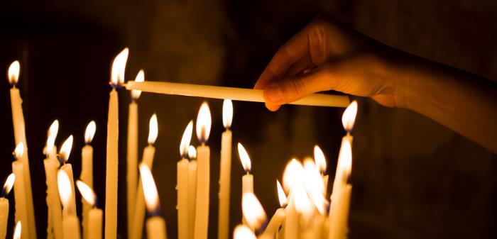En kvinna tänder ett ljus i en kyrka.
Bilden är nedladdad från Shutterstock