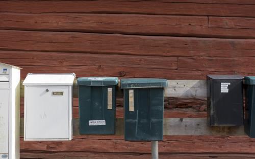 Brevlådor utanför en röd husvägg.