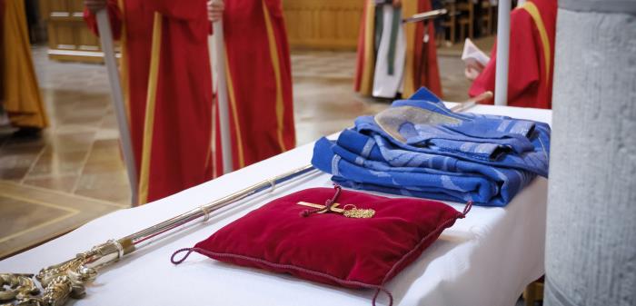 En spira, ett biskopskors och en blå ämbetsdräkt ligger på ett bord i Uppsala domkyrka.