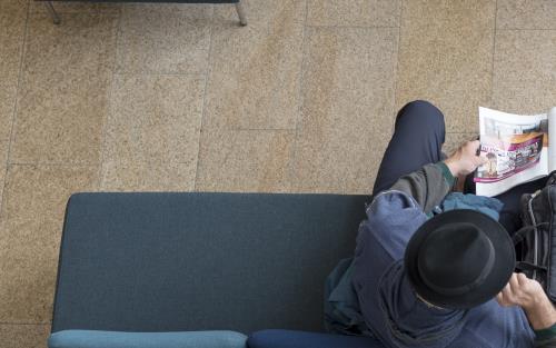 Två män fotograferade ovanifrån sitter i en soffa med varsin tidning.