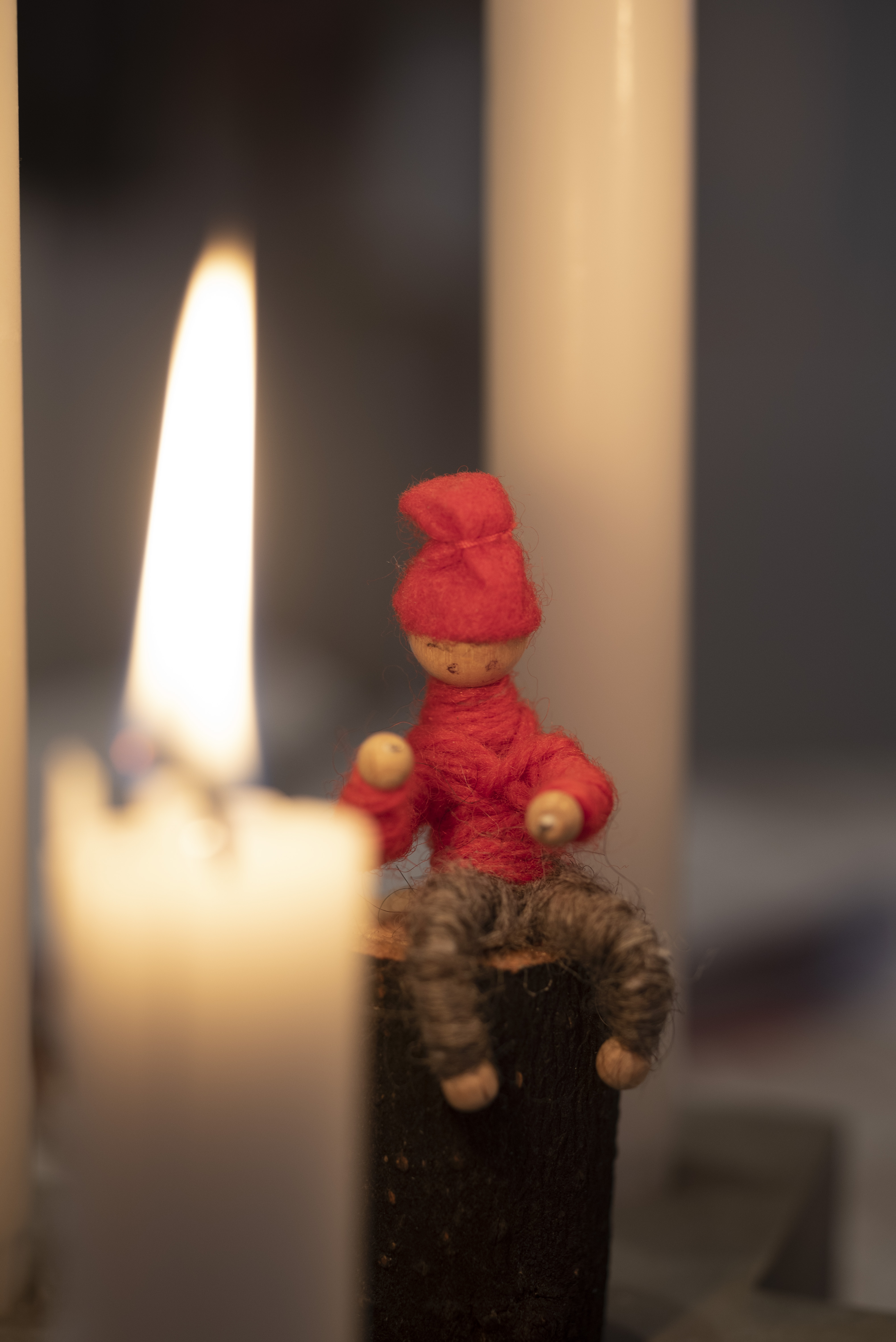 Ett tänt stearinljus och en liten tomte.