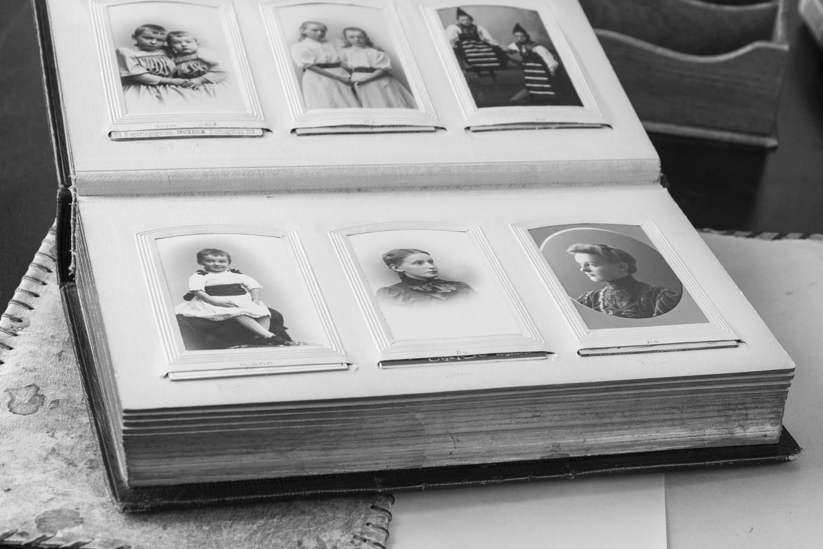 Svartvit bild av ett gammalt fotoalbum med porträttbilder.
