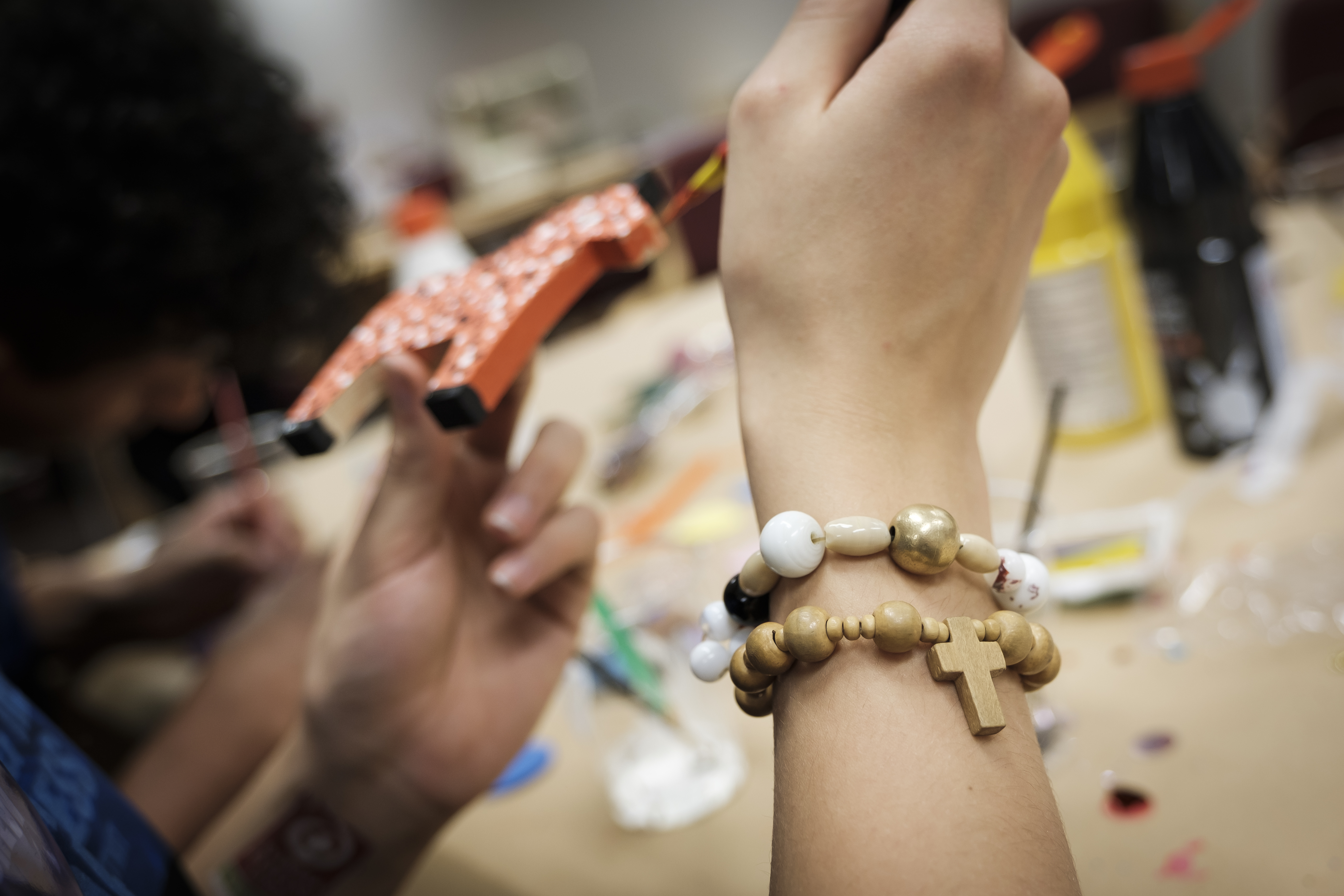 En person med ett korsarmband målar en liten trähäst.