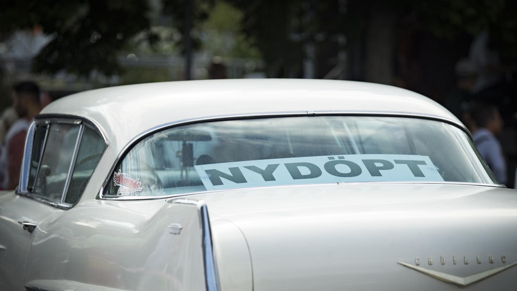 En skylt i bakrutan av en bil med texten Nydöpt.