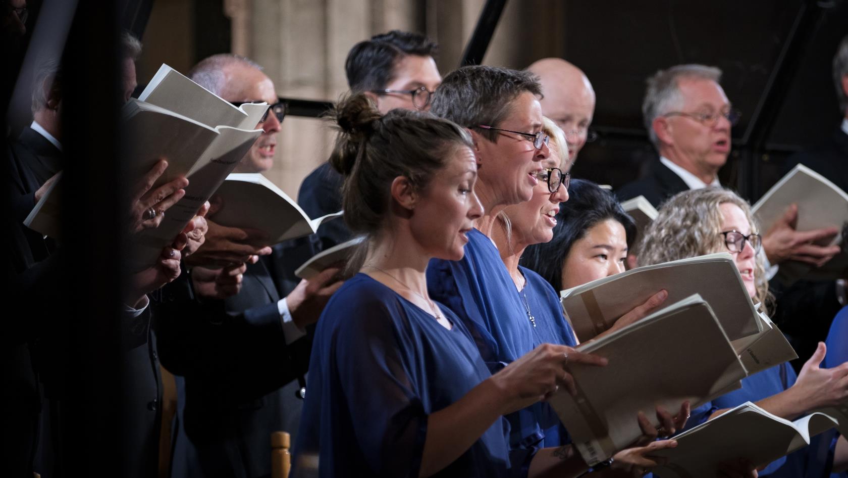 En blandad kyrkokör i matchande blå färger sjunger i Uppsala domkyrka.