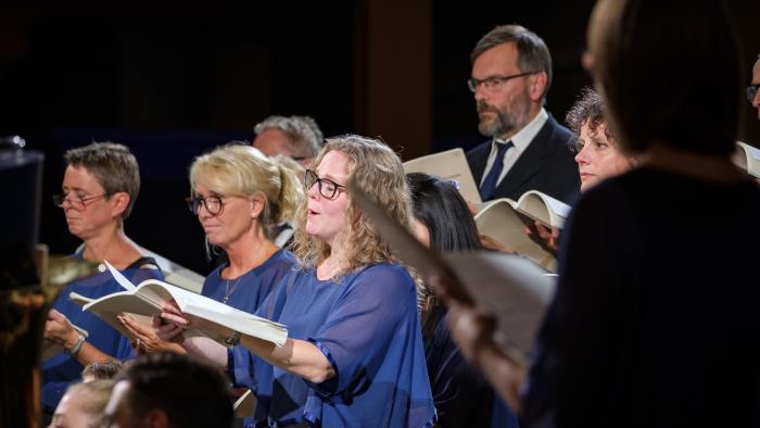 En blandad kyrkokör i matchande blå färger sjunger.