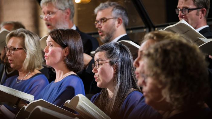 En blandad kyrkokör i matchande blå färger sjunger i Uppsala domkyrka.