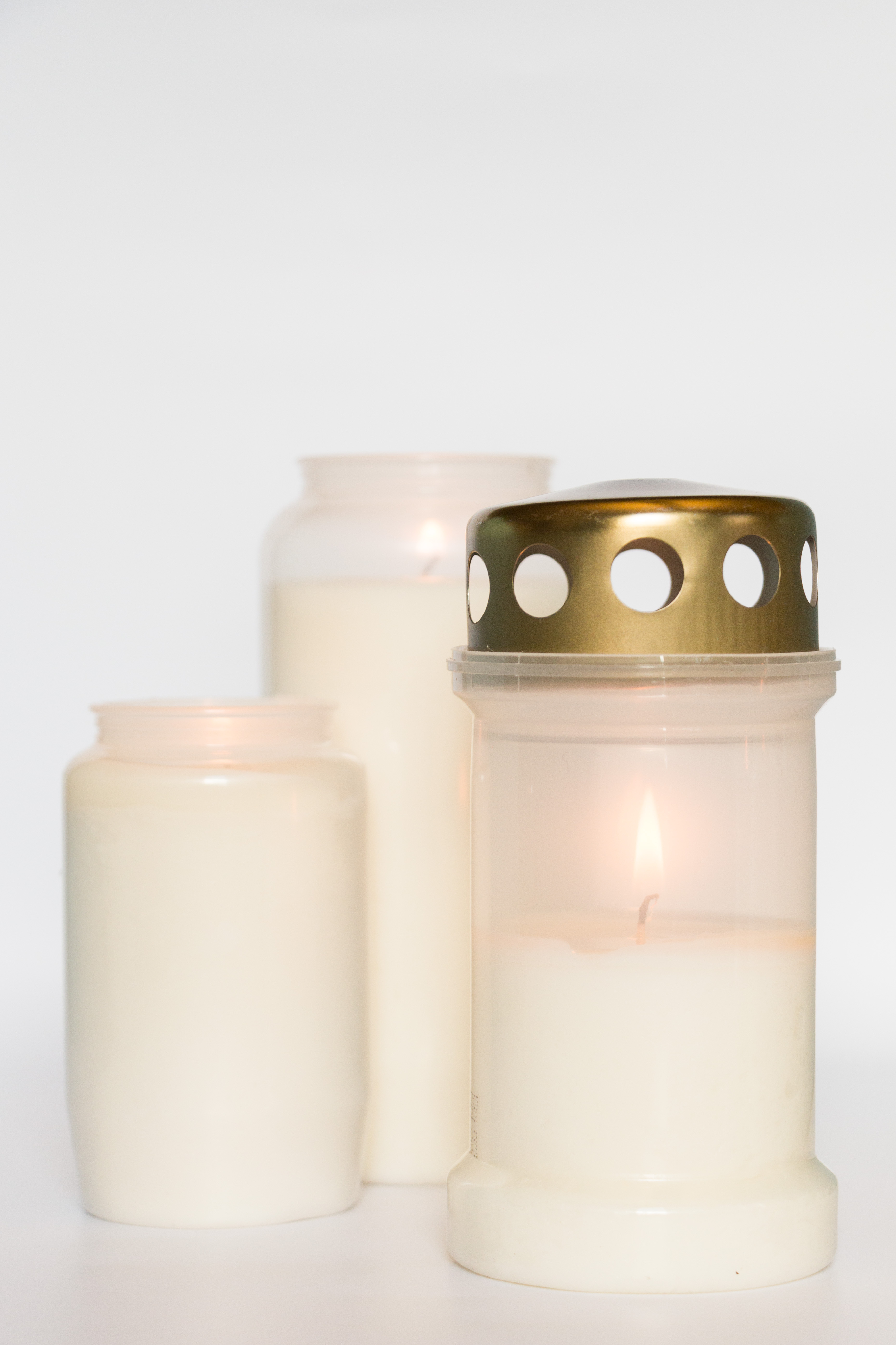 Tända gravljus mot vit bakgrund.