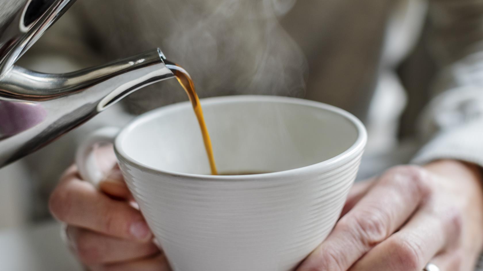 En person häller upp kaffe till någon som håller upp sin kopp.