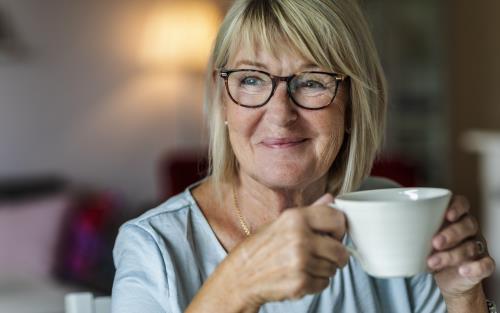 En blond kvinna dricker kaffe.