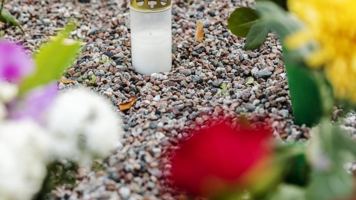 En massa blombuketter och gravljus står på en minneslund.