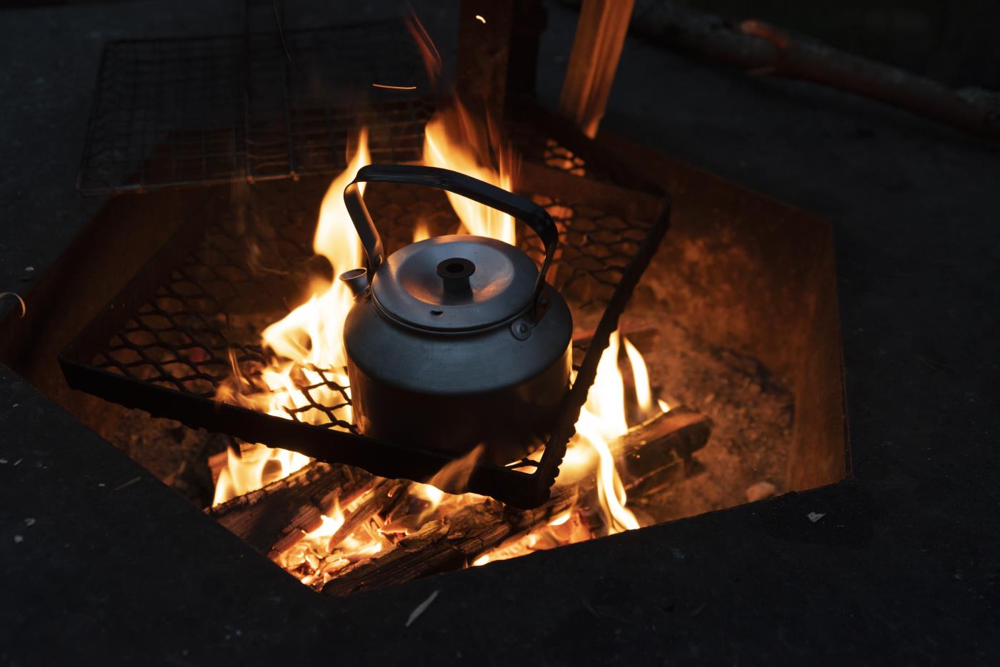 En kaffekastrull står på ett galler över den levande elden.