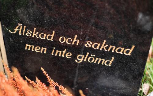 En svart gravsten med guldfärgad text: Älskad och saknad men inte glömd.