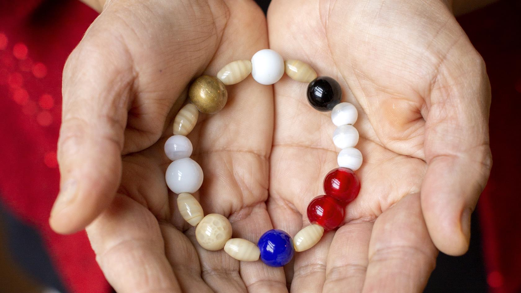 En person håller ett armband av olika pärlor i sina kupade händer.