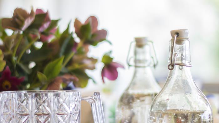 En karaff med saft och några glasflaskor vatten står på ett bord.