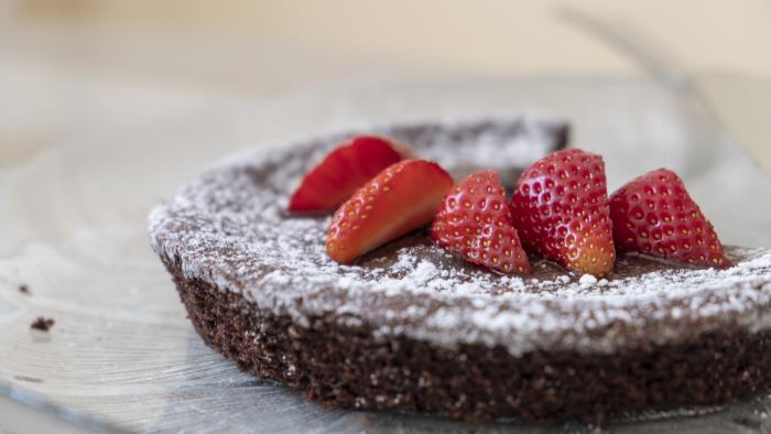 En kladdkaka toppad med florsocker och jordgubbar.